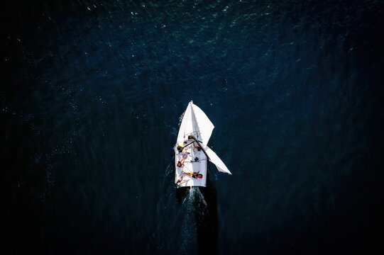 Sailing boat on a dark blue water, topdown (aerial drone photo). Strogino, Moscow, Russia