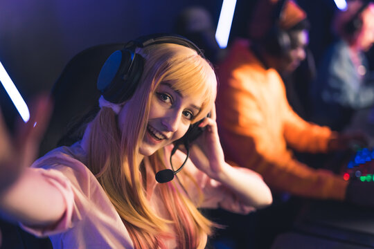 Blonde caucasian pretty woman in her 20s with a headset and microphone making a selfie during a online game tournament, sitting in a professional gaming room. High quality photo
