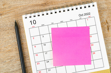 The Blank sticky note on October 2022 desk calendar on wooden background for your text.