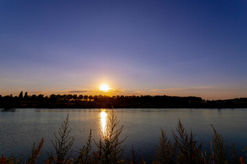 Landscape view with silhouette of tree along water, Twilight or blue hours in the evening after sunset, The Meuse or Maas is a major European river, Venlo is a city in the southeast of the Netherlands