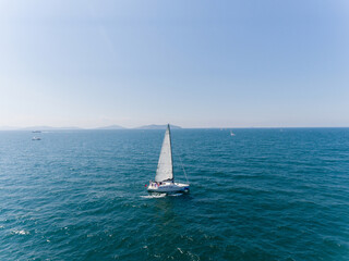 Aerial view of sailing ship yacht with white sails at deep open sea.
