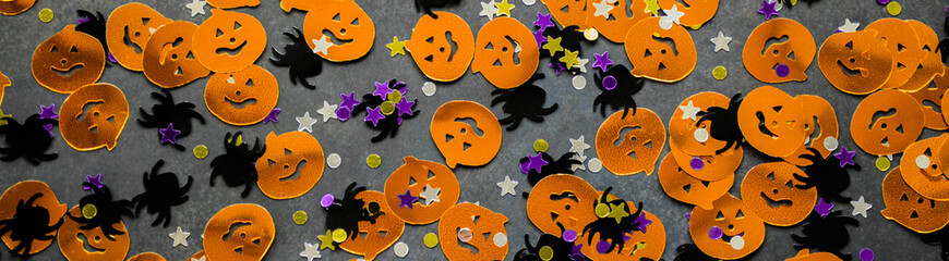 Banner Halloween background: shiny confetti in the shape of orange pumpkins, black spiders and colorful stars green, purple color
