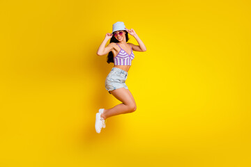 Full length photo of shiny sweet girl dressed swimsuit bra cap jumping high empty space isolated yellow color background