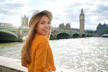Beautiful girl in London, UK. Portrait of young stylish woman in orange shirt and hat looking at...