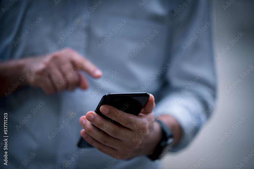 Poster close up on casual man using smart phone, using mobile smart phone and online working on laptop comp