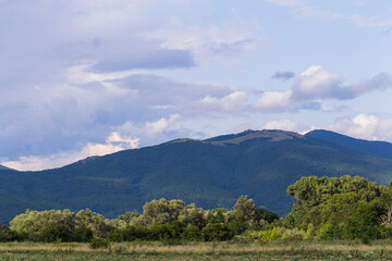 Fototapeta premium Thunderhead covers the Balkans. Downpour is approaching agricultural land. Villages, fields and forests of Bulgaria before the rain. The terrain in southern Europe. Panorama.