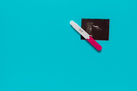 positive pregnancy test with ultrasound image on a blue background