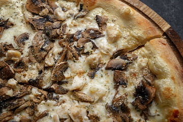 Pizza with mushrooms and chicken on a wooden board