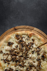 Fototapeta na wymiar Pizza with mushrooms and chicken on a wooden board. vertical
