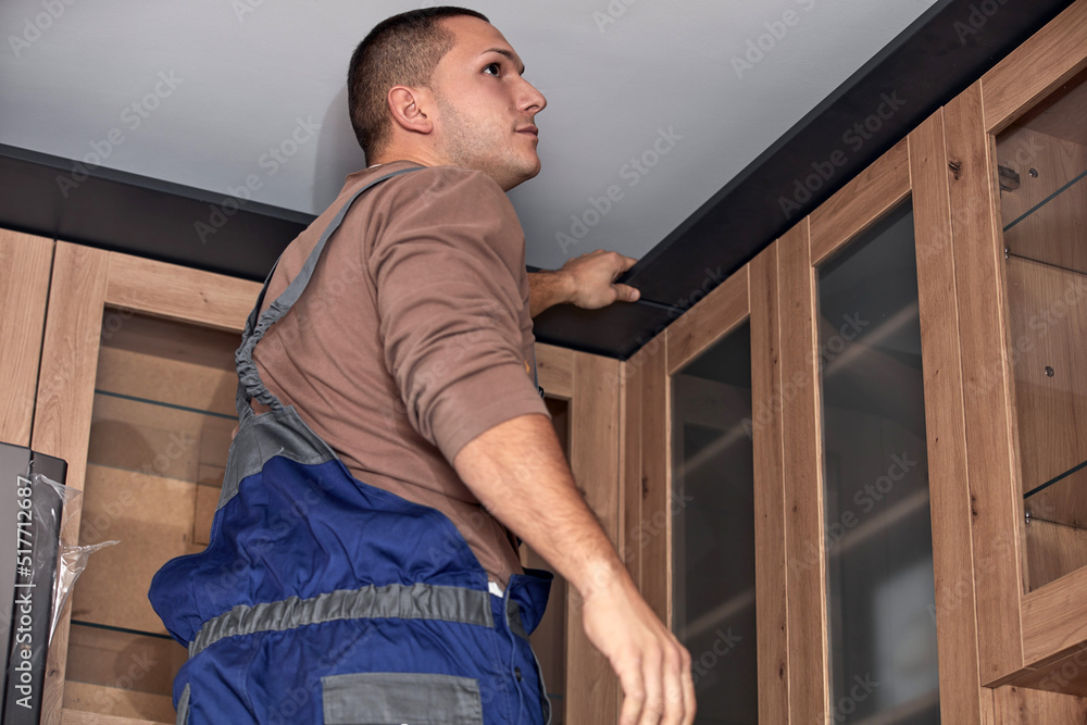 Wall mural handyman making kitchen wall cabinets in the apartment.