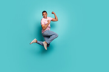 Fototapeta na wymiar Full length photo of cool strong man dressed pink t-shirt rising fists jumping high empty space isolated turquoise color background