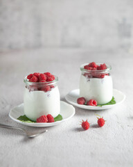 two jars of dessert with raspberries on the table