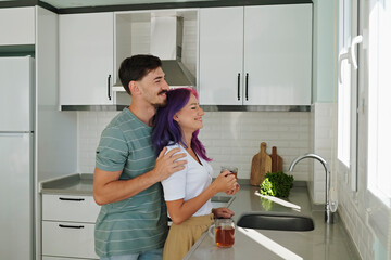 Young woman with colorful hair and her husband in the open plan kitchen of their new home. Hipster...