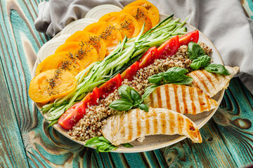 quinoa salad with grilled chicken and vegetables on wooden rustic background