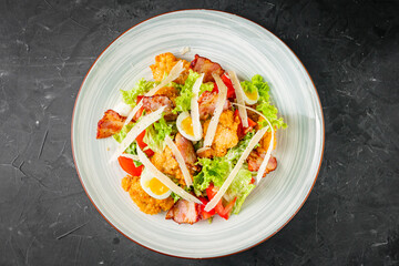 salad with fried chicken and bacon on a black background
