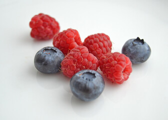 Raspberries and blueberries on a white background. Fresh raspberries and blueberries isolated on white background.