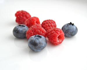 Raspberries and blueberries on a white background. Fresh raspberries and blueberries isolated on white background.
