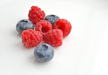 Raspberries and blueberries on a white background. Fresh raspberries and blueberries isolated on white background.