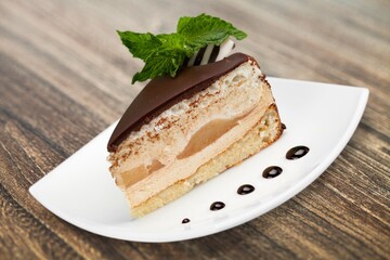 Tasty sweet cake decorated with fresh green mint leaf on white ceramic plate.Traditional dessert.