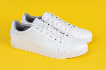Pair of new white sneakers on yellow background