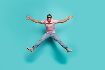 Fototapeta na wymiar Full length photo of excited pretty man dressed pink t-shirt jumping high like star isolated turquoise color background
