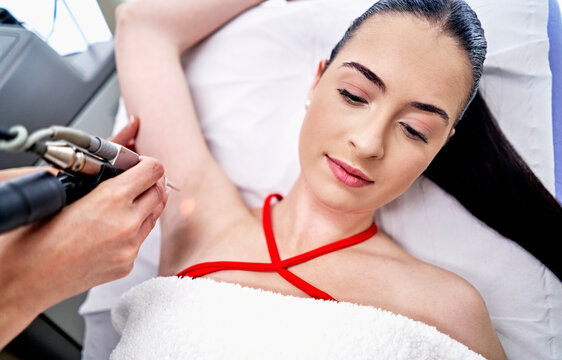 Esthetician epilating armpit of woman