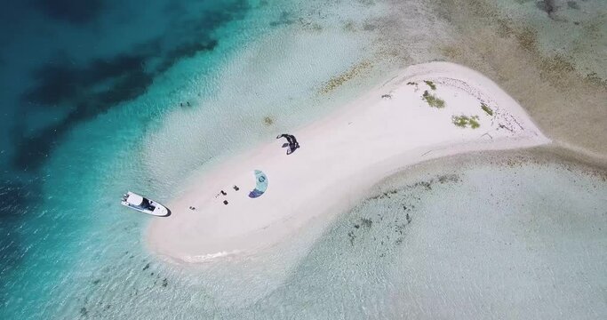 TOP DOWN Atoll with two Kitesurfers on white sand beach to kitesurf in azure, Los Roques