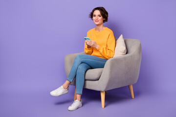 Full size portrait of positive nice person sit chair hold use telephone gadget isolated on purple color background