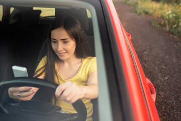 Young woman is using a smartphone while driving a car.