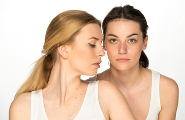 beauty portrait of two young attractive blonde and brunette girls on a light background isolated