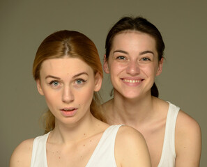 beauty portrait of two young attractive blonde and brunette girls on a light background isolated