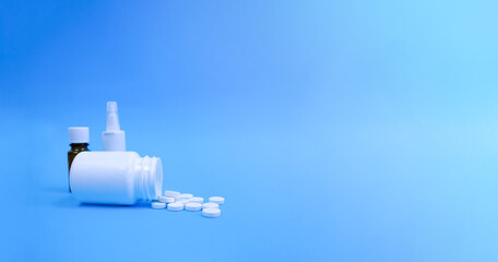 A bottle with pills and other medicines on a blue background. Copy space.