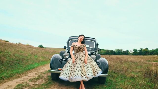 Young happy smiling sexy woman in pin-up style clothes posing hand raised explosion gesture. Vintage polka dot white dress, red high heels. road green grass spring summer nature. Girl fashion model
