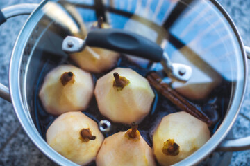 Peeled ​​stew pears in a pan ready to be stewed with cinnamon and red wine.
