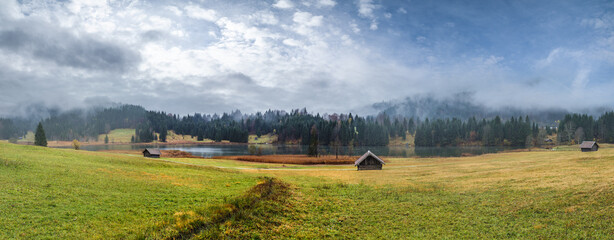 Fototapeta premium Alpine lake Geroldsee or Wagenbruchsee, Bavaria, Germany. Autumn overcast, foggy and drizzle day. Picturesque traveling, seasonal, weather, and rural nature beauty concept scene.