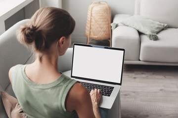 Young woman using laptop computer with white mockup screen at home. Freelance, student lifestyle, education, technology and online shopping concept.