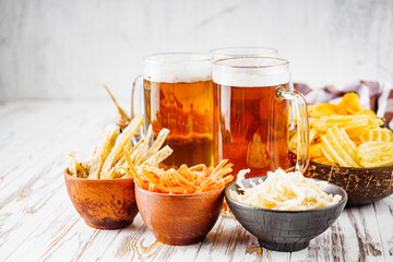 mug of beer and a set of dry fish snacks on a white wooden rustic background