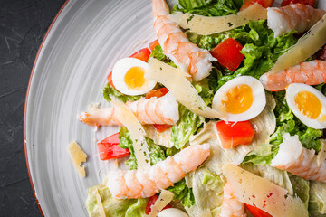 fresh salad with shrimp and parmesan on a black background