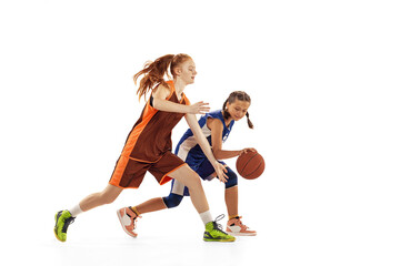 Studio shot of beginner basketball players, young girls, teen training with basketball ball isolated on white background. Concept of sport, team, enegry, competition, skills