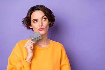 Portrait of attractive minded curious girl holding in bank card deciding copy space isolated over...
