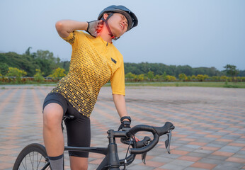 Asian female cyclist having neck pain from riding a bike long time. Poor posture is a major...