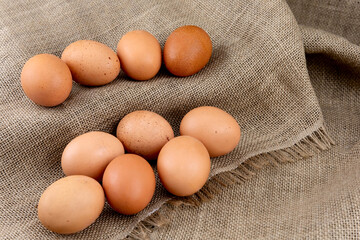 Fresh chicken brown eggs on burlap background, top view