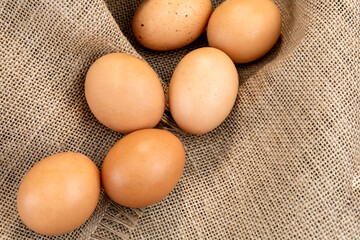 Fresh chicken brown eggs on burlap background, top view