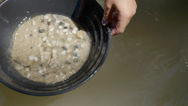 Children using gold pans to look for gems in sand in slow motion