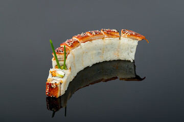 The dragon roll with eel and cheese on black with reflection