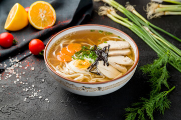 Ramen soup with noodles and chicken in the plate on black table