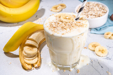 Vegan banana drink, healthy diet snack. Banana oatmeal smoothie in glass, with oats flakes and...