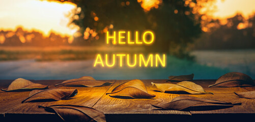 Fallen leaves on a wooden table with neon lighting text. Hello autumn concept © Mr. Music