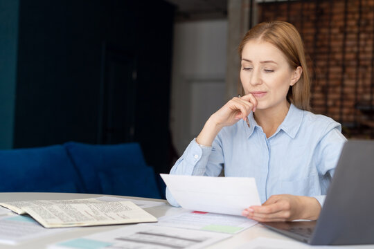 Puzzled businesswoman reading document in home office
