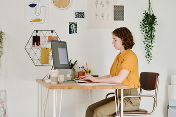 Young serious female freelancer or webdesigner concentrating on work over creation of new website...